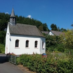 Kleine schiefergedeckte Kapelle mit weißem Verputz und rundem Türmchen