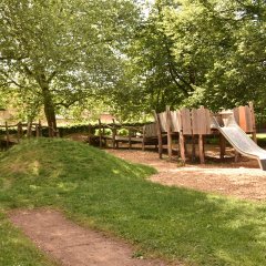 Spielplatz auf dem Schulhof mit verschiedenen Holzspielgeräten in Antikoptik