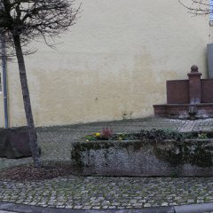 Sandsteindorfbrunnen mit alanggestrecktem Sandsteintrog davor