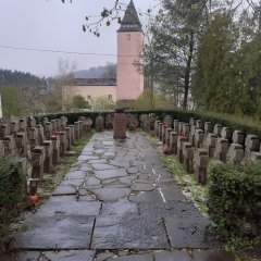 Ehrenfriedhof mit vielen Grabsteinen und Blick auf die Kirche