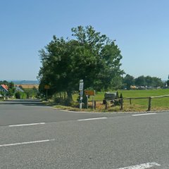 Einfahrtsstraße nach Orsfeld mit Wegekreuz und Häusern im Hintergrund