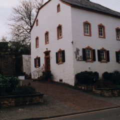 dreistöckiges Pfarrhaus mit Pfarrkirche im Hintergrund