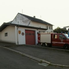 einfaches Feuerwehrgerätehaus mit Feuerwehrauto davor
