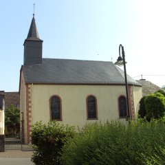 Schiefergedeckte kleinere Kirche mit drei Rundfenstern und kleinem Spitzturm