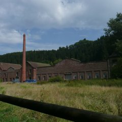 Fabrikgebäude in Ziegelbauweiße und alleinstehender Schornstein davor