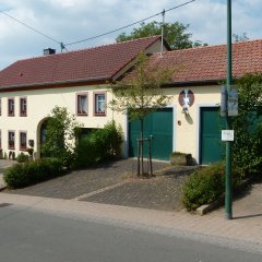 Feuerwehrgerätehaus mit zwei grünen Toren und Wohnhaus daneben